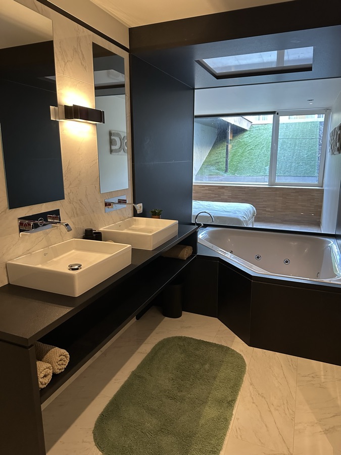 Badezimmer mit Doppelwaschbecken, Spiegelwand und Whirlpool-Badewanne