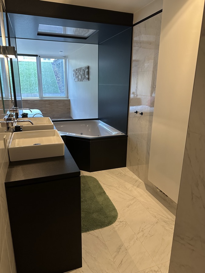 Bathroom with whirlpool bath, washbasin and marble floor