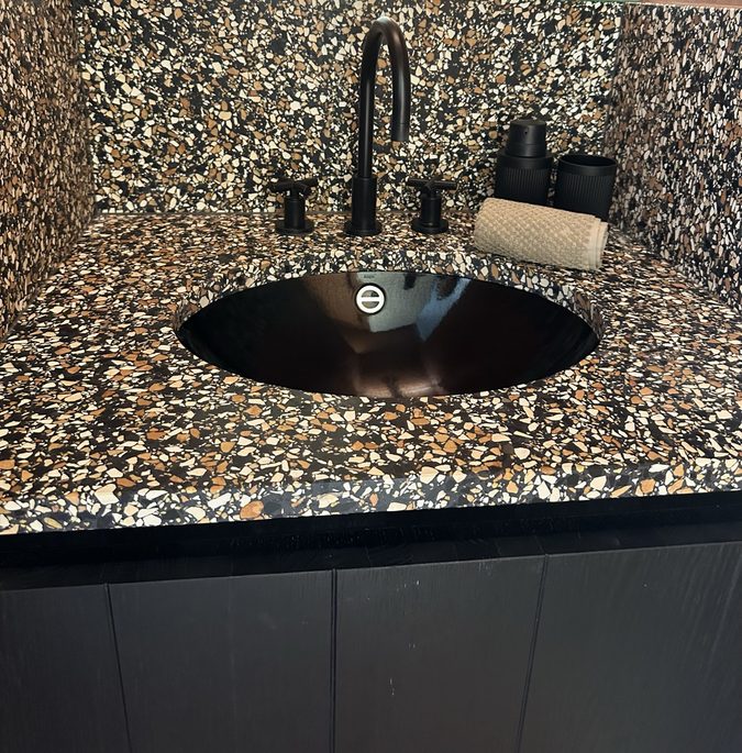 Black washbasin and tap on a granite top, close up