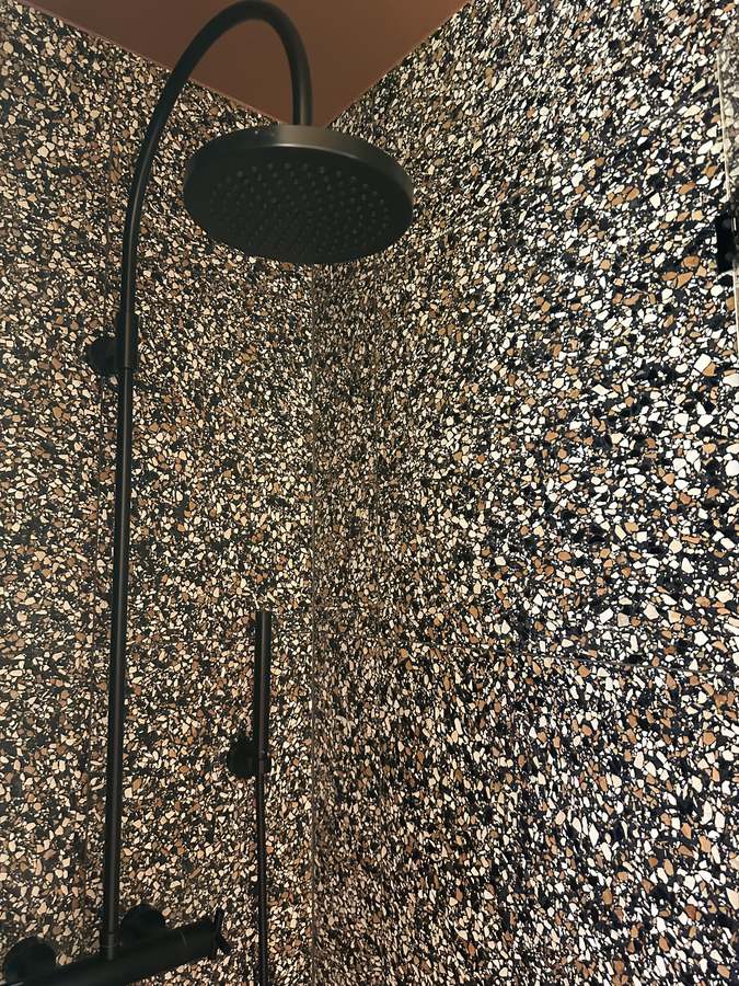 Black rain shower head and hand shower in the terrazzo walk-in shower