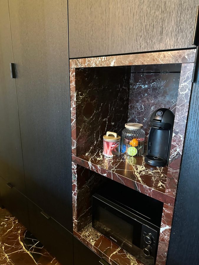 Coffee corner with a coffee machine, storage jars and a microwave in the kitchen cabinet