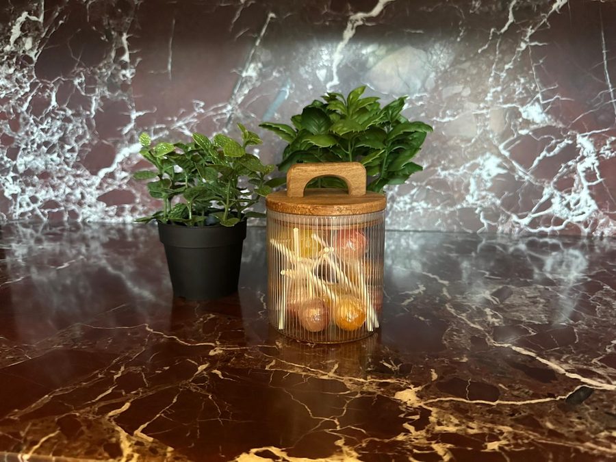 Glass storage jar with lollipops and plants on the red marble worktop