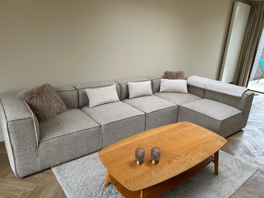 Modular corner sofa with cushions and an oak coffee table on herringbone parquet