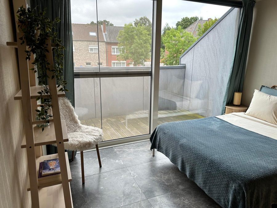 Bedroom with sliding doors onto the terrace, a ladder shelf and a sheepskin chair
