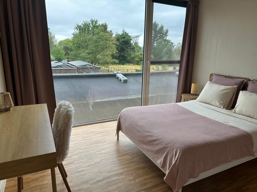 Bedroom with a desk, sheepskin chair and sliding doors onto the roof terrace