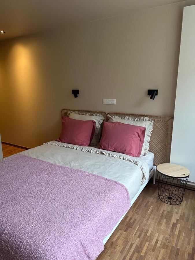 Bett mit Rattan-Kopfteil, rosa Plaid und rundem Beistelltisch
