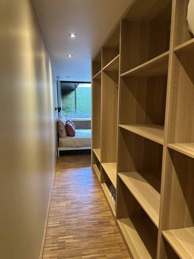 Oak walk-in wardrobe with a view through to the bedroom
