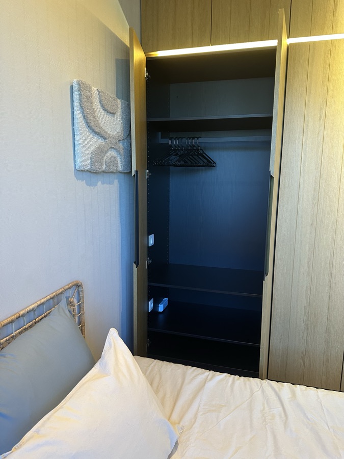 Open oak wardrobe next to the bed