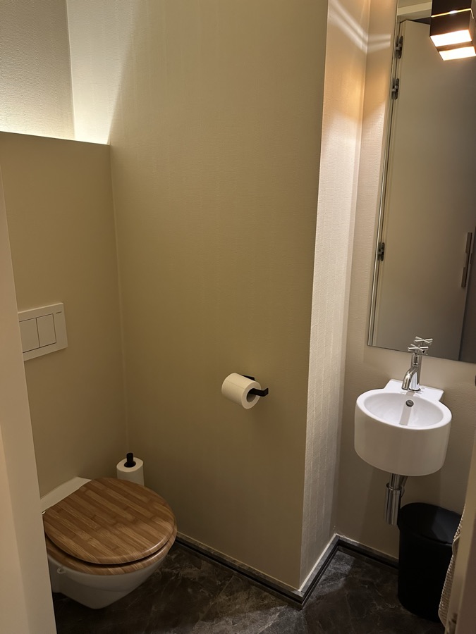 Separate toilet with a wooden seat and hand basin